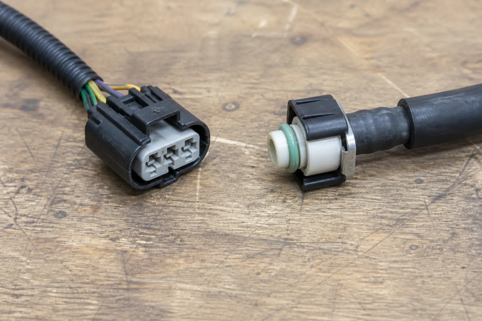 Fuel pump electrical wiring plug compared with a fuel-line quick-connect fitting on a shop bench
